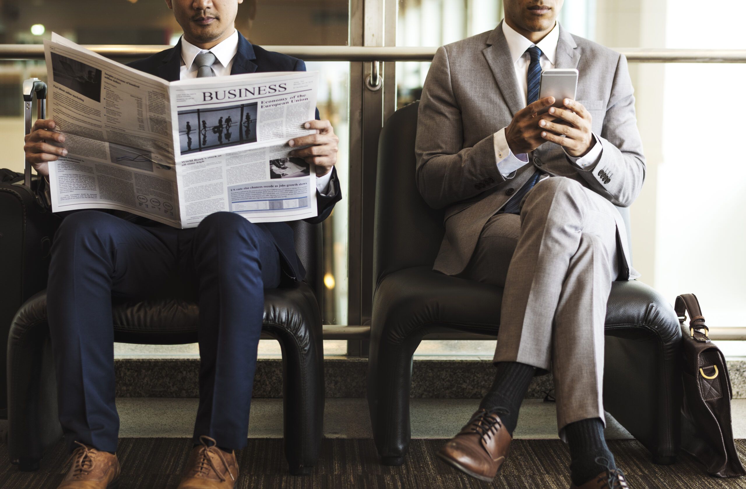 Männer lesen Nachrichten in Zeitung und Handy