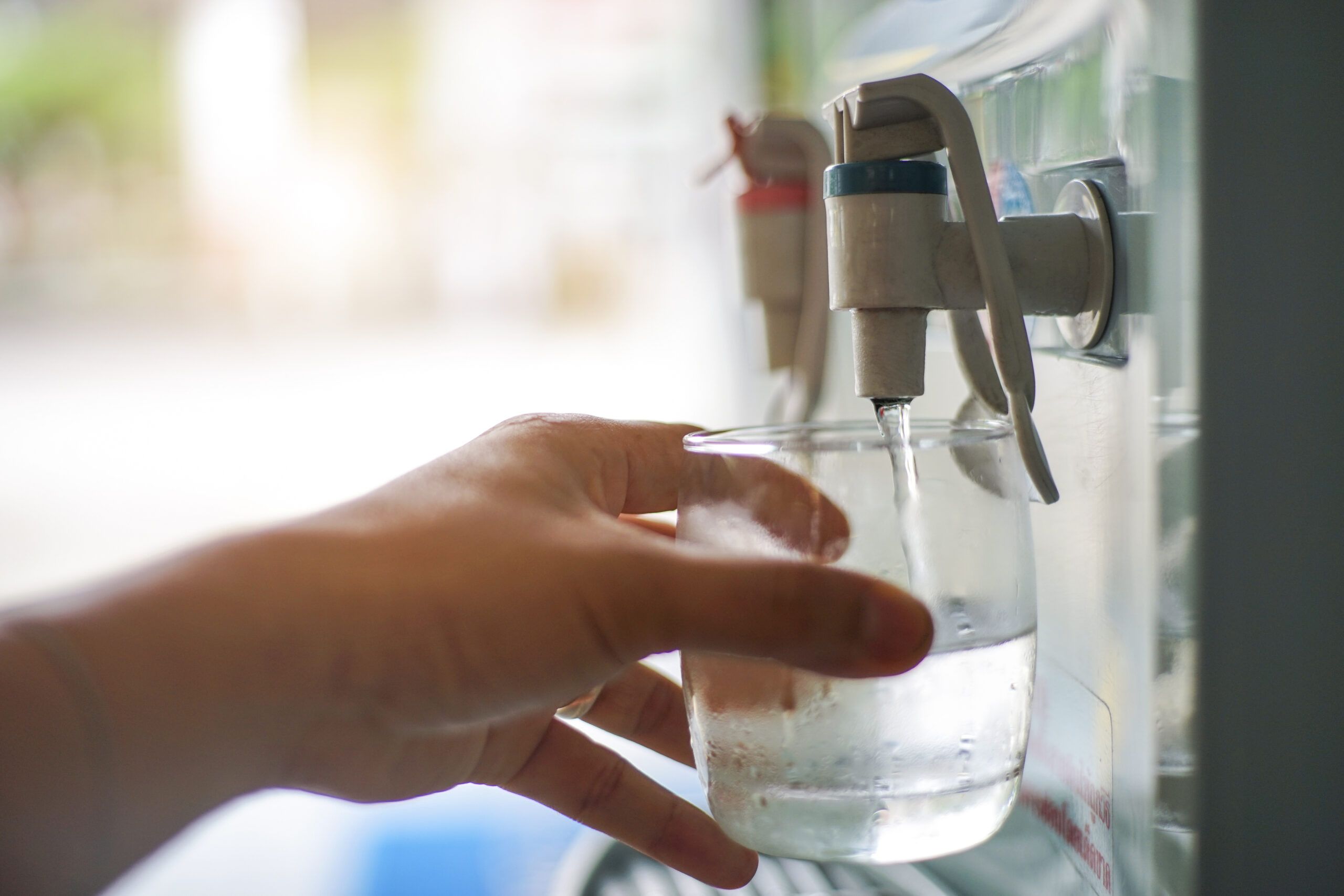 Frauenhand zapft kaltes Wasser aus Zapfhahn